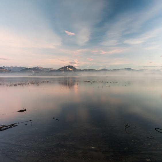 personal-routine3 Mist over a still lake at sunrise, with mountains reflected in the water