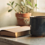 feel-like-yourself-again-featured A blue mug and an open book on a sunny windowsill beside a potted plant
